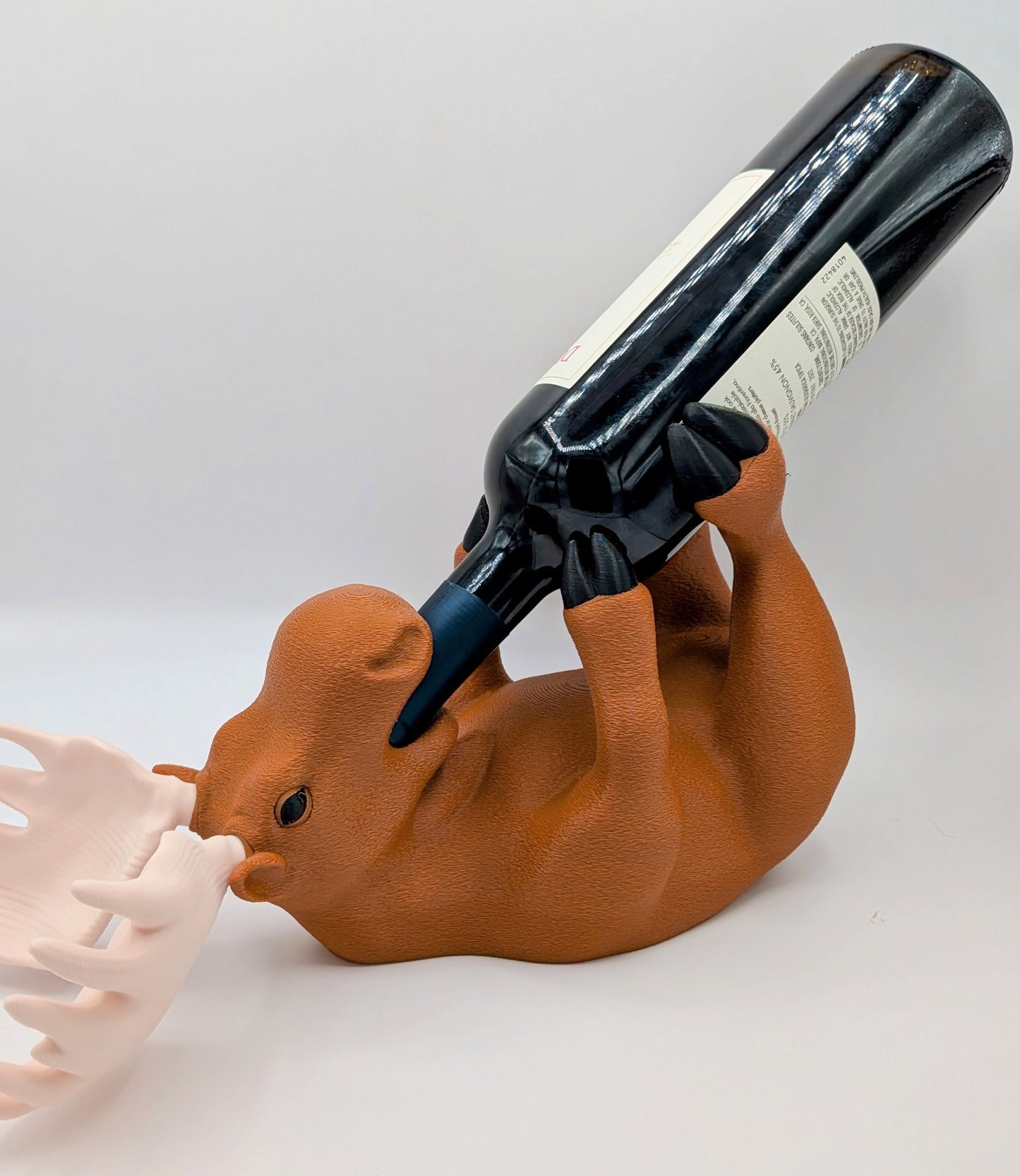 Charming 3D printed moose wine holder in a relaxed position, displaying a wine bottle upside down for playful home decor.